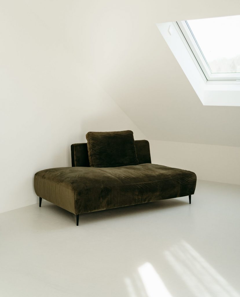 Foto aus dem studio liz. Unter einem Dachfenster steht ein dunkelgrünes Sofa.