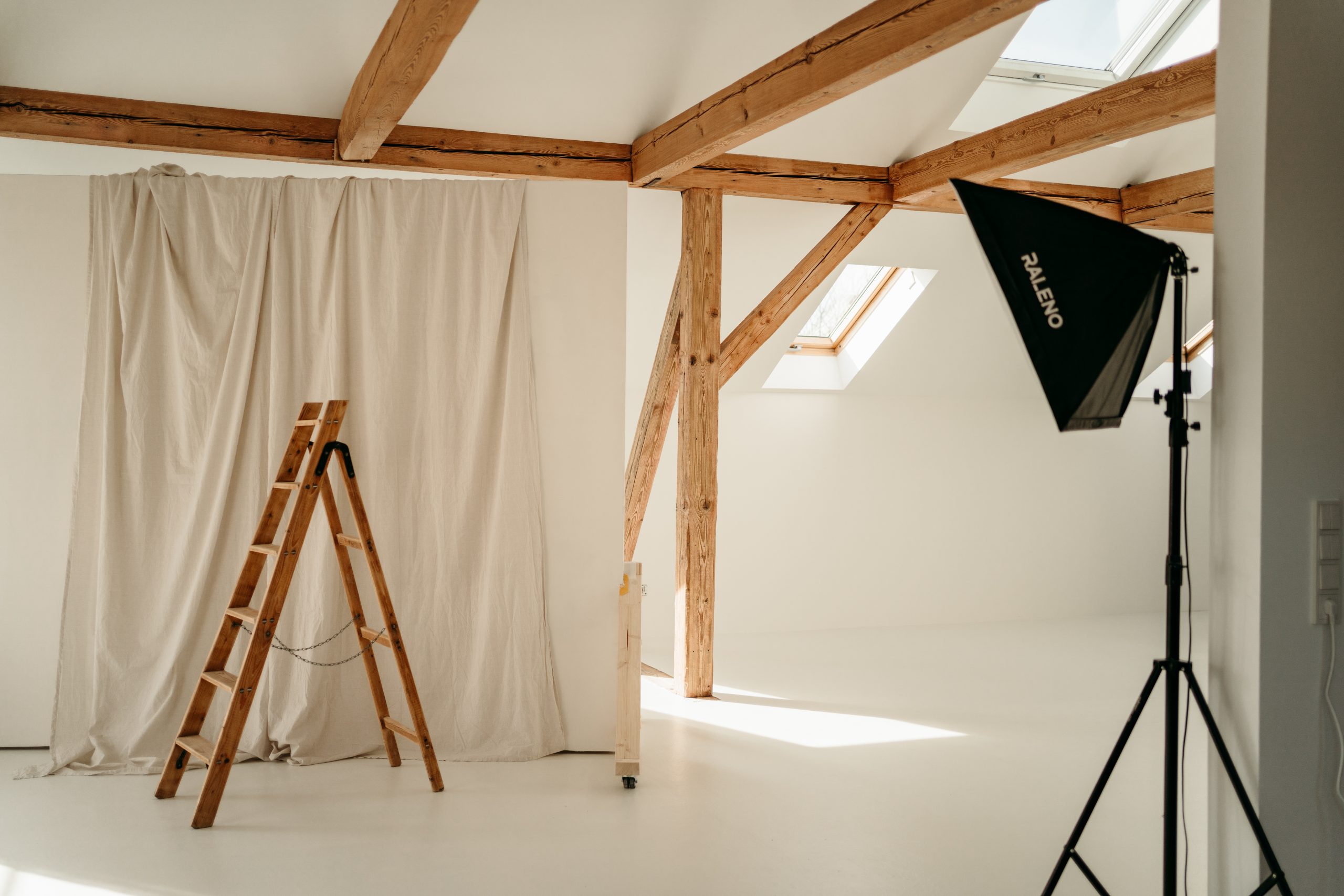 Foto aus dem studio liz. Zu sehen sind verschiedene Elemente, wie eine Holzleiter, die Leinwand und am Rand eine Softbox.