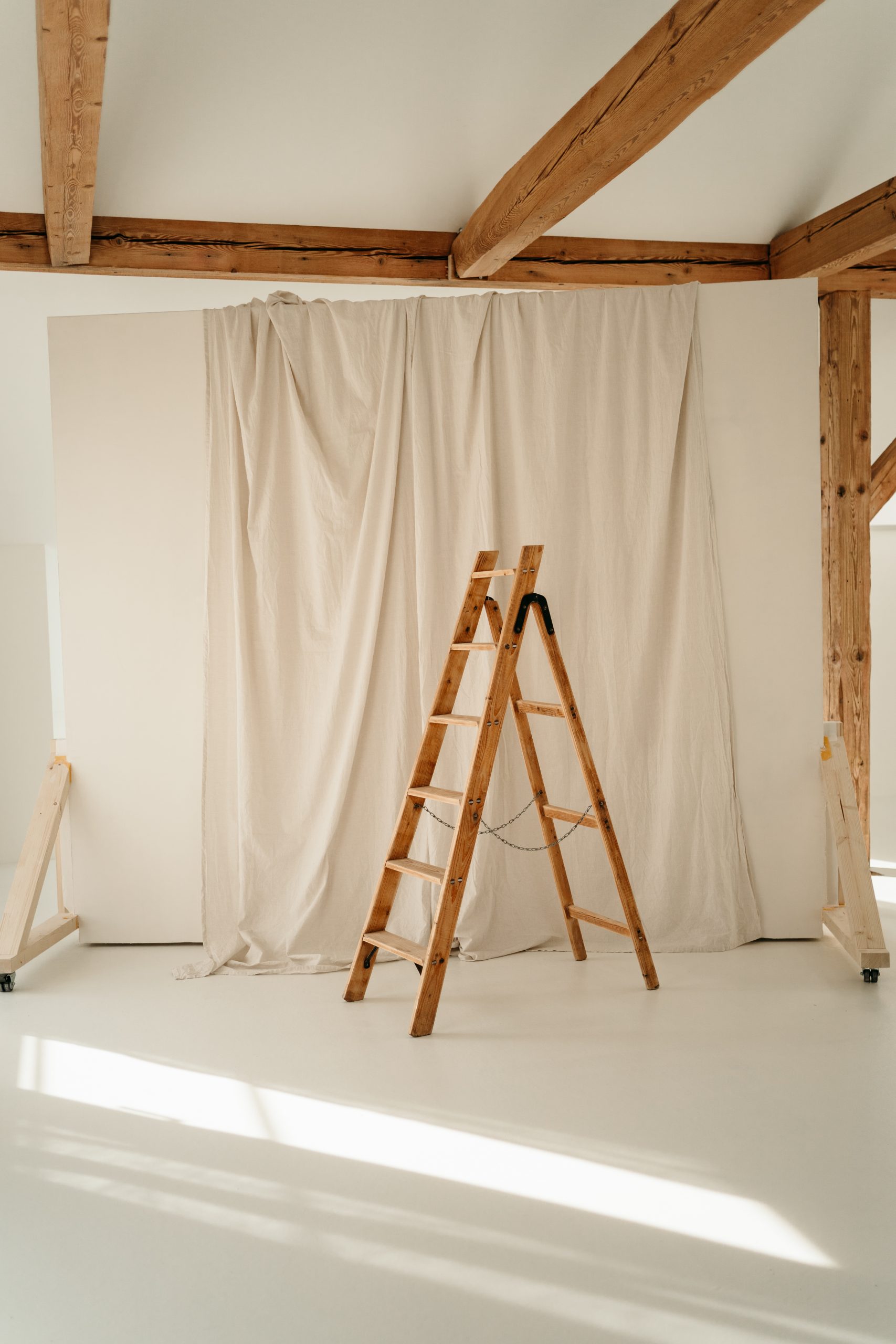 Foto aus dem studio liz. Im Zentrum ist eine Holzleiter, die vor einer Leinwand steht.