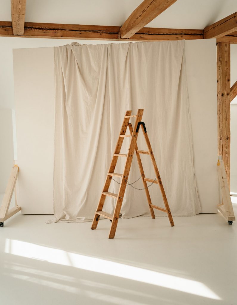 Foto aus dem studio liz. Im Zentrum ist eine Holzleiter, die vor einer Leinwand steht.